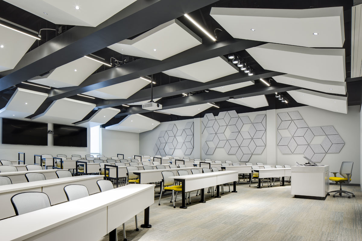A tiered classroom with angled baffles and yellow seated chairs for students as part of the healthcare design.